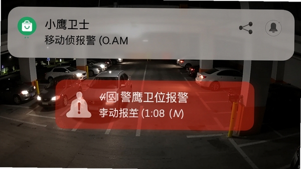 小鹰卫士报警推送界面，手机通知栏显示移动侦测报警，背景为夜晚的停车场监控视角，画面中有车辆灯光，突出警报信息的醒目显示