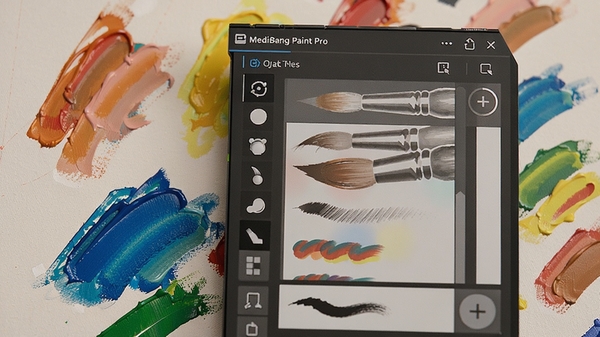 MediBang Paint Pro笔刷选择面板特写，展示多种形状的画笔图标与笔触效果预览，画布上呈现不同颜色的油彩笔触，光线柔和，突出软件丰富的笔刷库