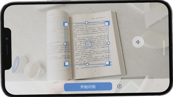 扫描文字提取软件文档矫正功能操作截图，手机界面显示一本打开的书籍，屏幕上的矩形矫正框覆盖在书页文字区域，界面下方有“开始识别”按钮，整体色调明亮干净