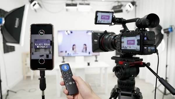 Tdx Teleprompter遥控与镜像模式使用场景,手机连接蓝牙遥控器,屏幕显示镜像字幕,旁边放置专业摄影设备,背景为明亮的直播间,体现高效便捷的录制流程