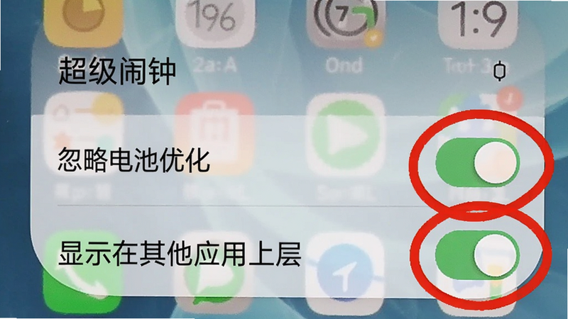 手机屏幕截图显示超级闹钟的权限设置页面，背景是一张模糊的手机桌面，重点突出“忽略电池优化”和“显示在其他应用上层”两个开关为绿色开启状态，周围用红色圆圈标注，画面简洁明了。