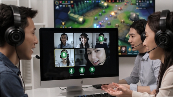 YY语音多人语音通话场景，电脑屏幕前几个戴耳机的用户正在热烈讨论，界面显示多人绿色麦克风图标亮起，背景虚化的游戏画面，展现流畅沟通氛围
