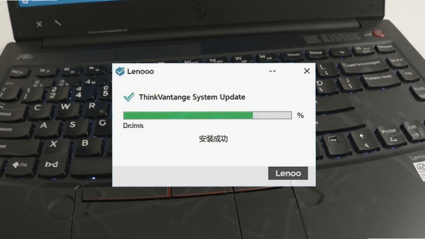ThinkVantage System Update正在安装驱动的过程截图，显示进度条与“安装成功”提示，背景为联想笔记本键盘特写，光线明亮，风格写实，传递出安全可靠与高效的感觉