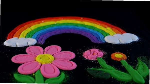 我爱沙画画 彩色沙画作品展示，画面中有多种颜色的沙画图案，如彩虹、花朵，背景为深色，色彩明亮饱和