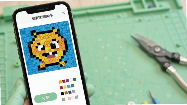 像素拼豆图助手预览与分享功能演示，手机屏幕显示一幅完成的像素画作品，下方有分享按钮与色号清单，背景为淡绿色工作台，整体风格清新，软件名称像素拼豆图助手清晰可见