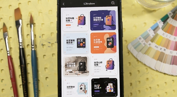 比艺智能模板选择界面,手机屏幕展示多套不同风格的设计模板缩略图,背景为淡黄色的工作台,旁边散落着画笔和色卡,体现比艺的便捷创作体验