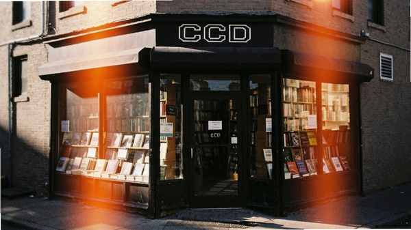 CCD复古像素相机Pro特效展示，一张带有明显胶片颗粒和橙色漏光效果的复古照片，画面主体是街角的旧书店，光线从窗户斜射进来，颗粒感明显，漏光效果自然，营造出浓郁的怀旧氛围，细节锐利