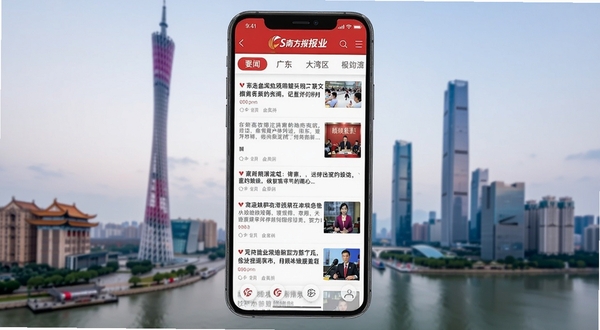 South南方Plus应用主界面全景展示，画面中央为手机屏幕内呈现新闻资讯瀑布流布局，顶部导航栏包含要闻、广东、大湾区等频道标签，背景为广州塔与珠江新城城市天际线虚化处理，整体色调以南方报业标志性的红色与白色为主，体现权威媒体气质与岭南地域特色