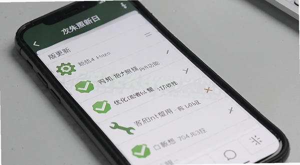 户外照明手电筒软件更新日志展示图,手机屏幕显示版本更新内容列表,背景为简洁的浅灰色桌面,配有绿色对勾图标,强调新版功能的优化与修复。