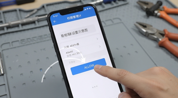 易相联安装设置界面示意图，手机屏幕显示权限管理页面，手指正在点击允许按钮，背景为简洁的灰色工作台，突出操作指引感