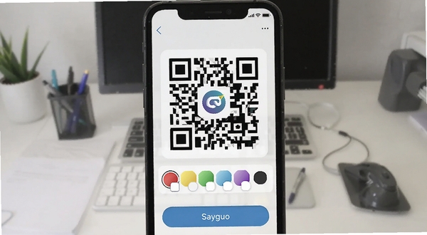 二维码与条形码软件生成功能界面，手机屏幕上显示一个带有中心Logo的彩色二维码，下方有颜色选择器和保存按钮，背景为办公桌面，适配Boogu模型生成