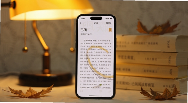 画面中央一部智能手机竖屏展示已阅App的阅读界面，背景是温馨的暖黄色台灯与堆叠的纸质书籍，周围散落几片秋叶，整体色调柔和治愈，体现沉浸式阅读氛围，画面主体手机屏幕清晰显示已阅的文字排版与书签图标，背景区域虚化处理] <p style=