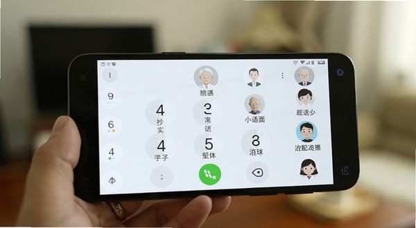 老人简用桌面超大字体功能演示,画面展示一部安卓手机屏幕,屏幕上显示着巨大的拨号键盘数字和联系人头像,文字标注清晰可见,背景虚化处理,突出适老化设计细节