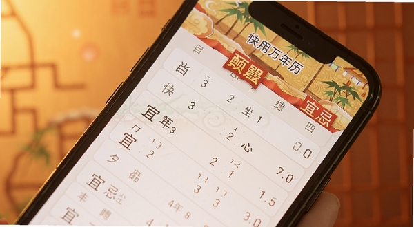 快用万年历黄历宜忌界面特写,画面主体为手机屏幕中显示当日宜忌列表,背景为柔和暖色调,突出传统文化氛围,软件名称快用万年历清晰可见