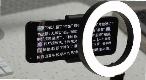 滚动字幕在手机支架上配合环形补光灯使用的场景图,手机屏幕显示滚动字幕,背景是简洁的桌面,画面清晰明亮