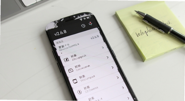 复盘盒子版本更新日志界面,手机屏幕显示版本号v2.6.8和更新条目列表,背景为简洁的白色办公桌面,旁边有便签纸和笔