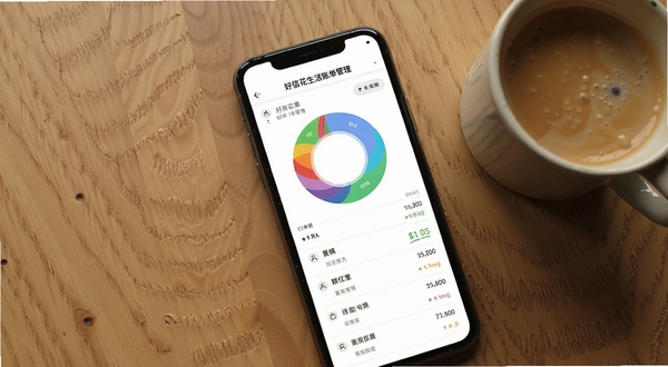 好信花生活账单管理界面,手机屏幕展示彩色分类环形图与账单列表,桌面背景为木质纹理,旁边放着一杯咖啡,营造日常记账的温馨氛围