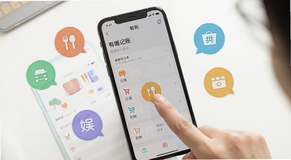 有喔记账软件功能展示图，画面中心是一部手机，屏幕显示有喔记账的智能分类界面，手指正点击餐饮图标，周围环绕着餐饮、交通、购物、娱乐等彩色分类气泡，背景为干净的白色桌面，光线明亮柔和，体现操作流畅与分类丰富