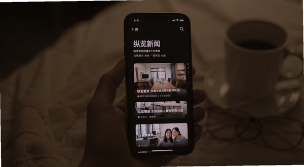 纵览新闻夜间模式阅读界面,深色背景上显示清晰的文字排版与新闻配图,手机屏幕发出柔和不刺眼的光芒,画面氛围安静舒适,纵览新闻预览图