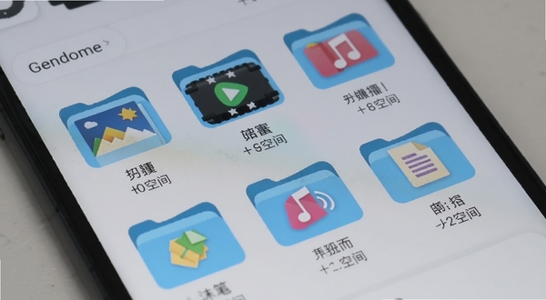 Gendome应用的文件管理界面,屏幕上排列着图片、视频、音频、文档等分类文件夹图标,每个图标下方标注文件数量和占用空间大小,界面背景为浅灰色,手机以略微倾斜的角度展示,光线柔和,突出文件清理功能的便捷性