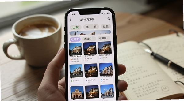 手机屏幕展示山东教育发布app收藏夹页面,分类标签清晰可见,背景为咖啡杯与笔记本,营造安静阅读氛围