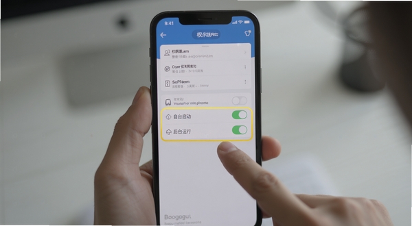 整点报时软件后台权限设置操作示意图，画面中央为手机屏幕显示应用权限管理页面，高亮标注自启动与后台运行两个开关按钮，背景区域为手持手机操作场景，手指点击屏幕动作清晰可见，整体风格写实自然，光线柔和，画面主体坐标居中，背景简洁不杂乱，适配Boogu模型生成