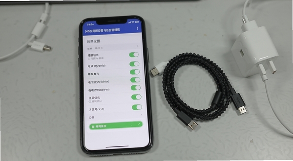360应用权限设置与后台管理界面，手机屏幕显示权限开关列表与电池优化白名单设置页，旁边放置数据线和充电器，背景为浅灰桌面，风格写实清晰，突出设置操作场景