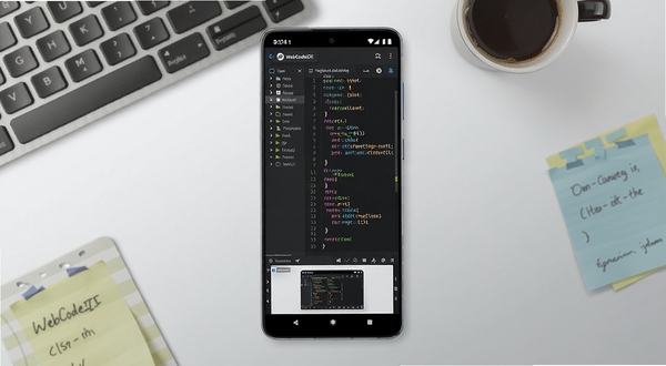 WebCodeIDE 软件全貌展示图，画面中央是一部竖屏安卓手机，手机屏幕上显示深色主题的代码编辑器界面，左侧为文件目录树，右侧为彩色语法高亮的代码区域，顶部有项目名称标签栏，底部为预览窗口，背景为浅灰色渐变的工作台环境，周围散落着键盘、咖啡杯和便签纸，整体风格现代简洁，突出移动编程的便携感，画面比例16:9，高清细节