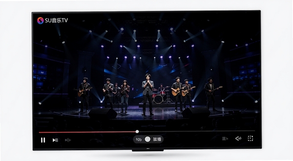 SU音乐TV高清MV播放界面，电视大屏上呈现舞台演出画面，底部为播放进度条与清晰度切换按钮，软件名称SU音乐TV显示在左上角，画面主体居中，背景为深色演播厅氛围