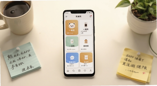 一摊熊APP主界面全貌展示,画面中央是一部竖屏安卓手机,屏幕上呈现一摊熊应用首页的卡片式功能布局,背景为浅暖色调的桌面环境,周围点缀生活化的小物件如咖啡杯、便签纸和绿植,整体风格清新简洁,突出便民工具属性,画面主体居中构图,背景虚化处理,适配Boogu模型生成